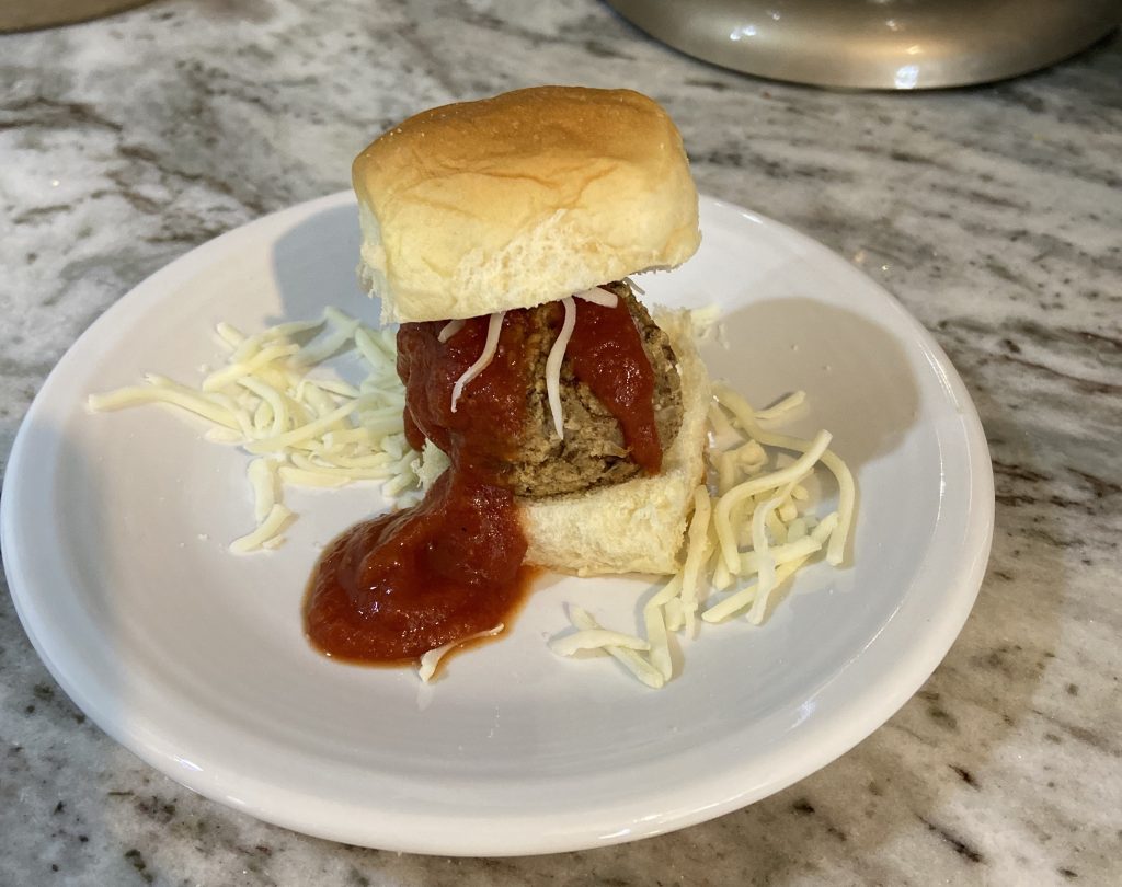 veggie meatball on slider bun with sauce and cheese on plate